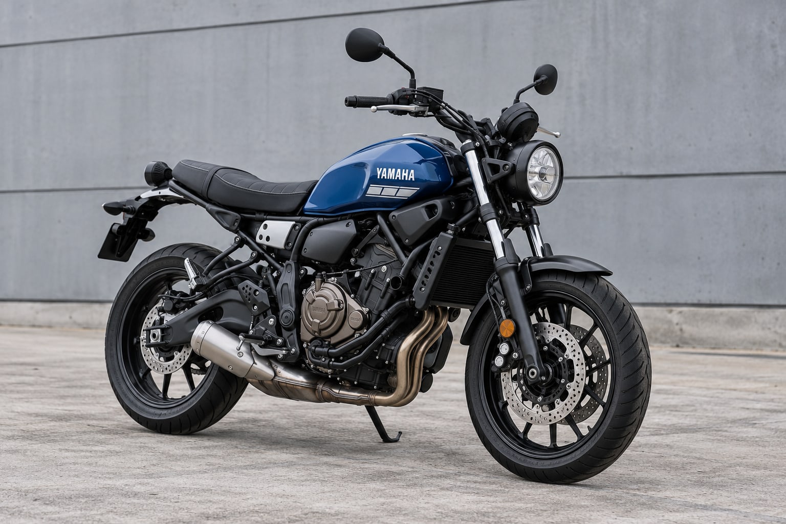 Blue Yamaha XSR700 motorcycle parked beside an industrial wall